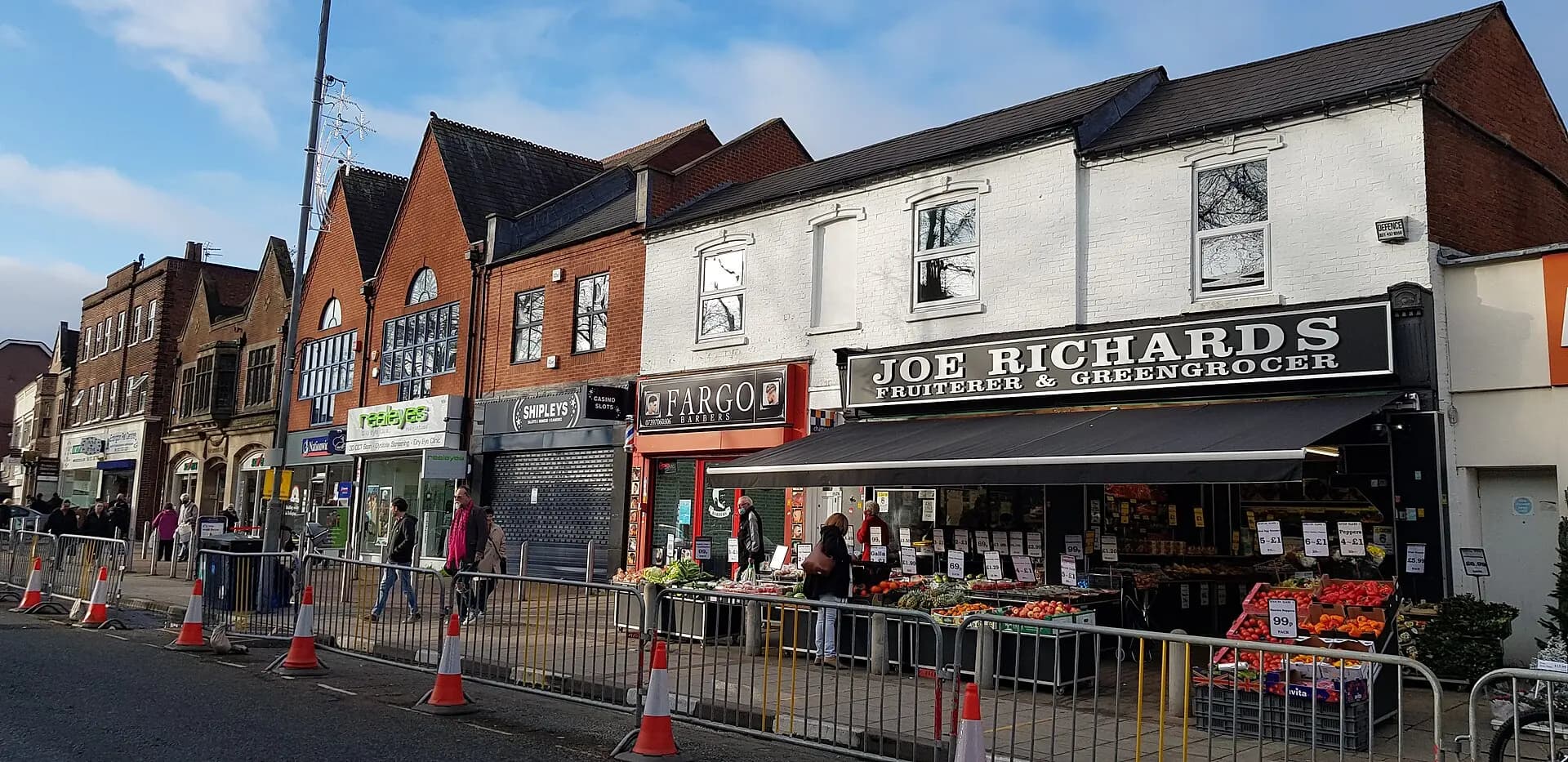 A parade of shops on Erdington High Street, with a greengrocer displaying produce outside.